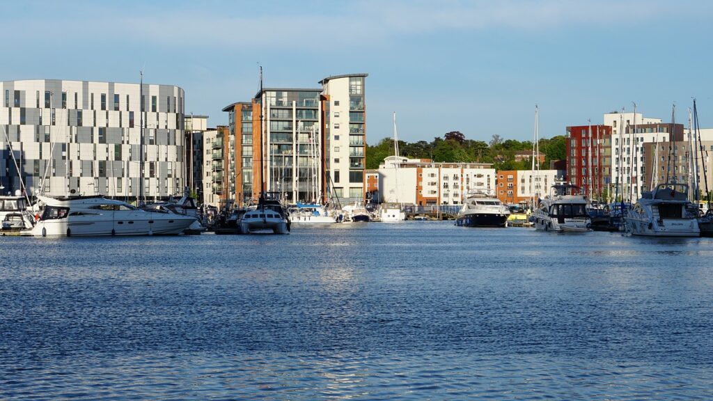 Scenic view of Ipswich Waterfront Marina in the UK, with modern apartment buildings, yachts, and boats docked on a sunny day.